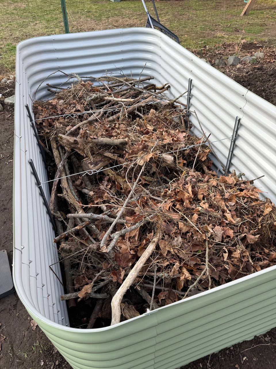 Birdies raised bed filled with branches, sticks, and dry oak leaves as hugelkultur base layer