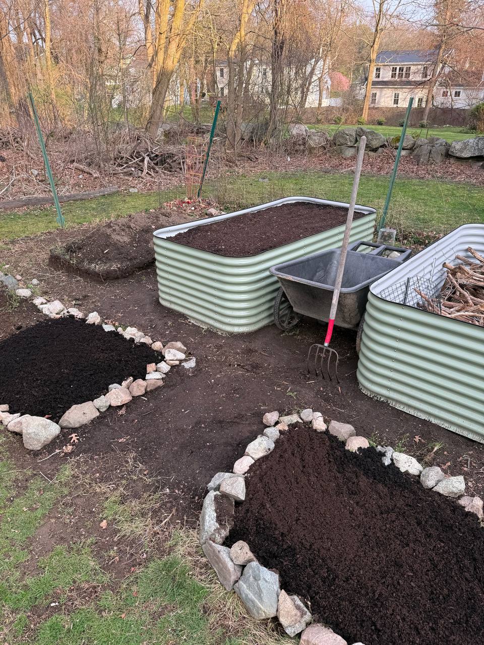 Young boy patting soil around freshly planted seedlings in a raised bed
